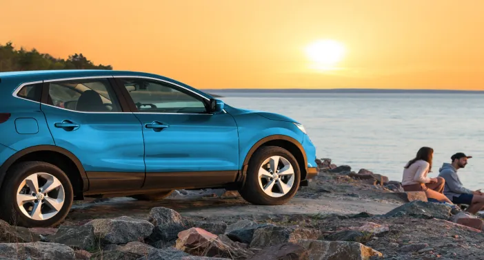 Blue SUV parked by the water at sunset